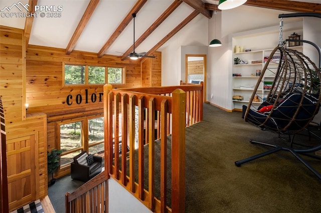 interior space featuring carpet flooring, a healthy amount of sunlight, beam ceiling, and wood walls