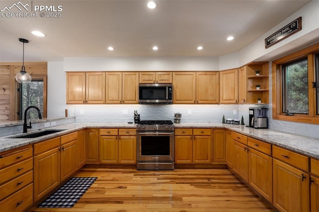 kitchen with pendant lighting, sink, appliances with stainless steel finishes, light stone counters, and light hardwood / wood-style floors