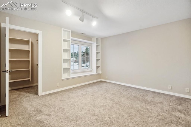 unfurnished bedroom with a walk in closet, carpet floors, a closet, and track lighting