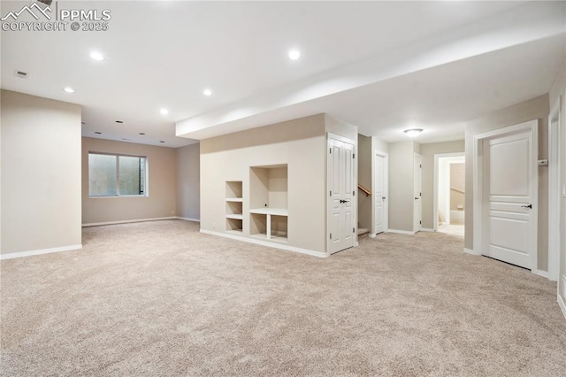 unfurnished living room featuring light colored carpet and built in features