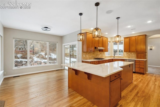 kitchen featuring a kitchen island, decorative light fixtures, dishwasher, backsplash, and gas cooktop