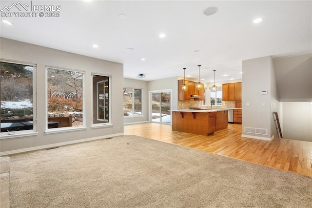 kitchen with decorative light fixtures, a kitchen bar, decorative backsplash, a center island, and light carpet