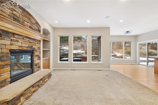 unfurnished living room featuring light carpet, built in features, and a fireplace