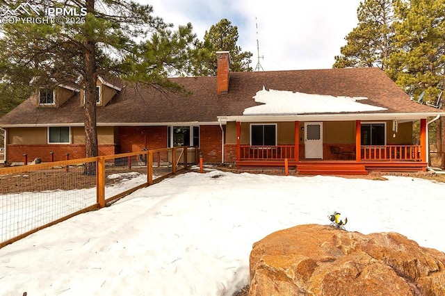 view of front of house featuring a chimney, fence, a porch, and brick siding