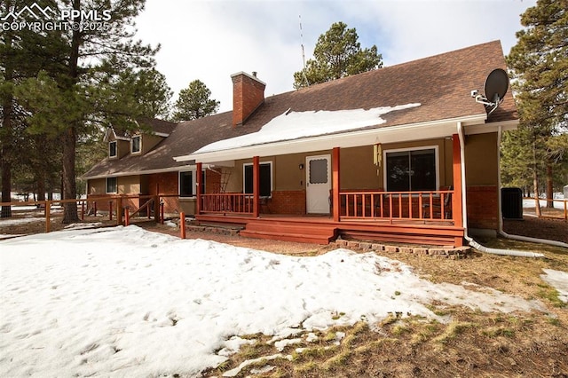 snow covered back of property featuring a porch