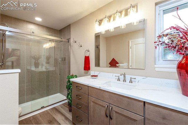 bathroom with a shower with door, hardwood / wood-style floors, plenty of natural light, vanity, and toilet