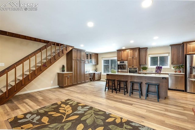 kitchen with a spacious island, stainless steel appliances, a kitchen bar, and light wood-type flooring