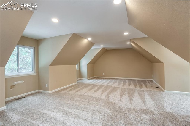 bonus room with lofted ceiling and light colored carpet