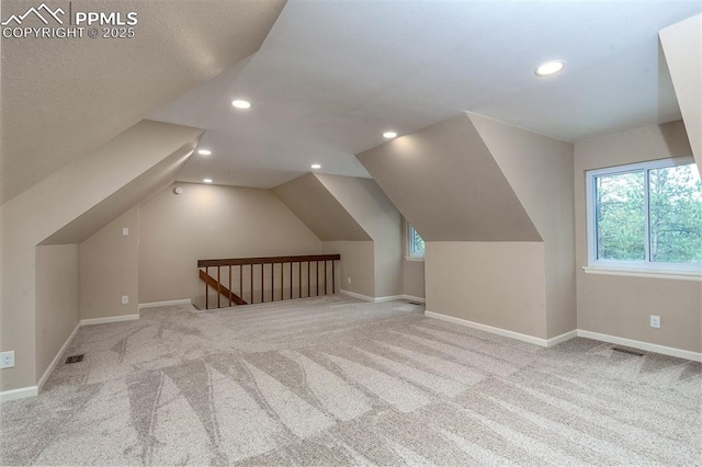 additional living space featuring vaulted ceiling and light carpet