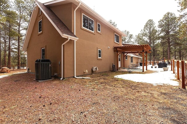 back of property with central AC unit, a pergola, and a patio area