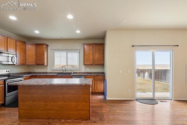 kitchen with stainless steel appliances, a kitchen island, dark wood-type flooring, and sink