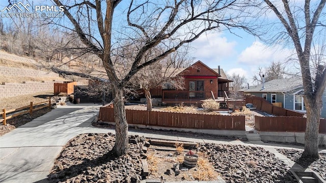 view of front of house with driveway, a fenced front yard, and a wooden deck