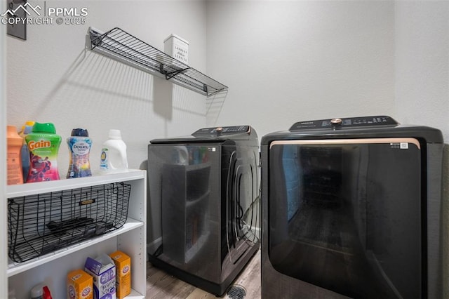 laundry room with washing machine and clothes dryer and wood-type flooring