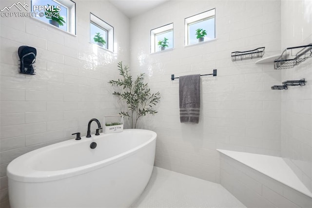 bathroom featuring tile walls and a tub