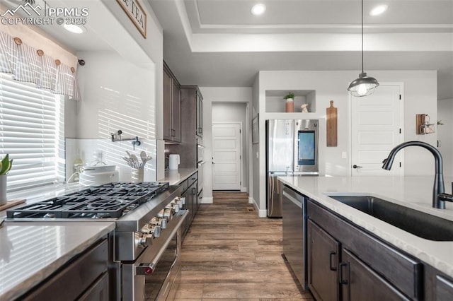 kitchen with dark brown cabinetry, sink, hanging light fixtures, appliances with stainless steel finishes, and dark hardwood / wood-style flooring