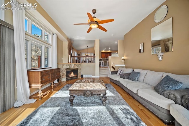 living room with ceiling fan, lofted ceiling, and light hardwood / wood-style flooring