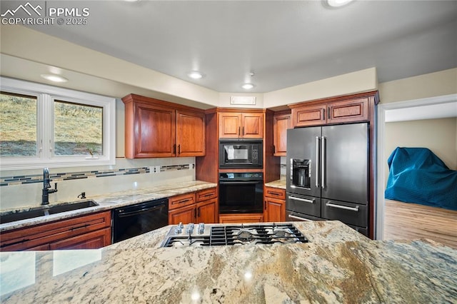 kitchen with sink, backsplash, black appliances, and light stone countertops