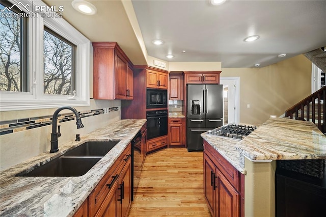 kitchen with sink, light hardwood / wood-style flooring, light stone counters, tasteful backsplash, and black appliances