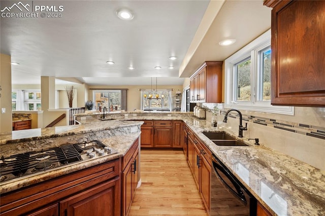 kitchen featuring stainless steel gas cooktop, sink, light stone counters, dishwasher, and pendant lighting