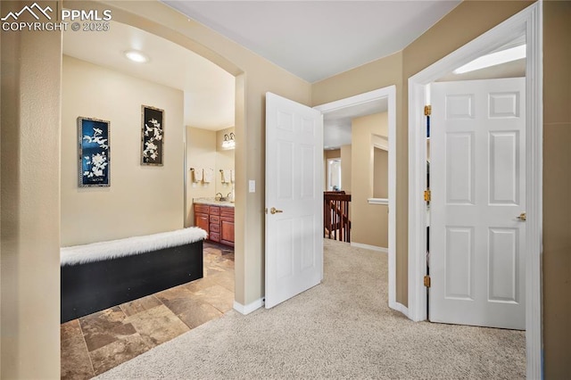 hall with sink and light colored carpet