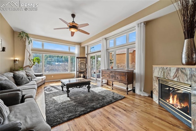 living room with ceiling fan, a fireplace, and light hardwood / wood-style floors