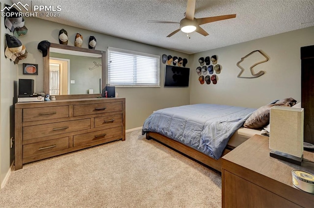 carpeted bedroom with ceiling fan and a textured ceiling