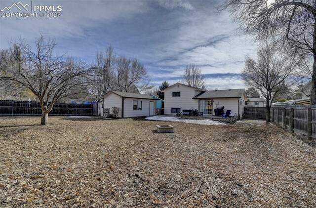 rear view of property featuring an outbuilding, a patio area, and a fire pit