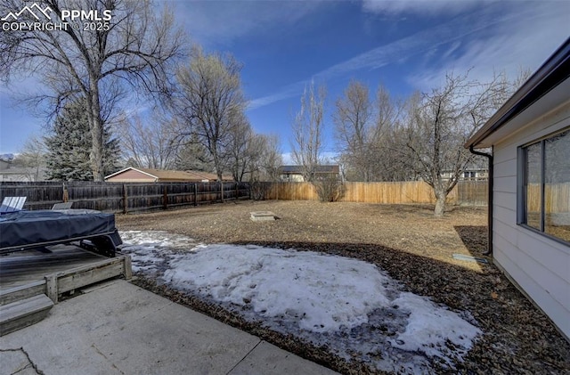 yard layered in snow with a patio area and a hot tub