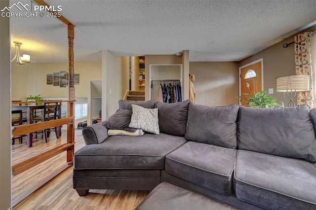 living room with an inviting chandelier, wood-type flooring, and a textured ceiling