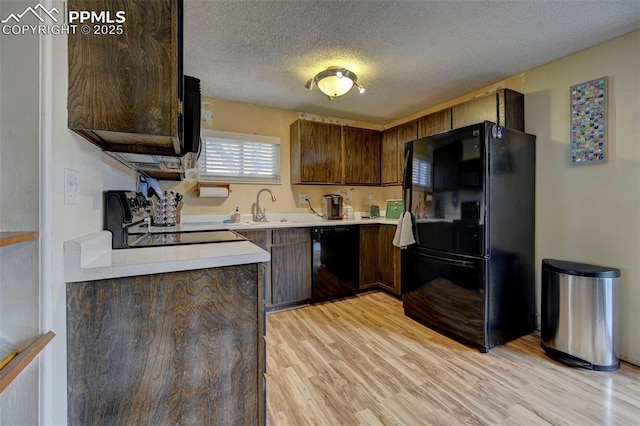 kitchen featuring sink, a textured ceiling, light wood-type flooring, dark brown cabinets, and black appliances