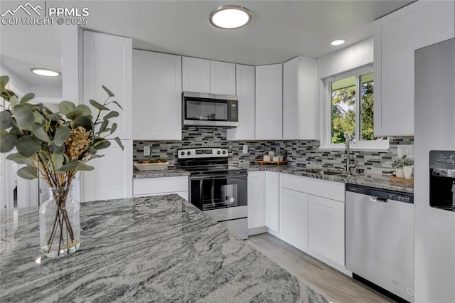 kitchen with light stone countertops, white cabinets, and appliances with stainless steel finishes