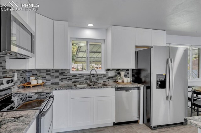 kitchen featuring light stone countertops, appliances with stainless steel finishes, sink, and white cabinets