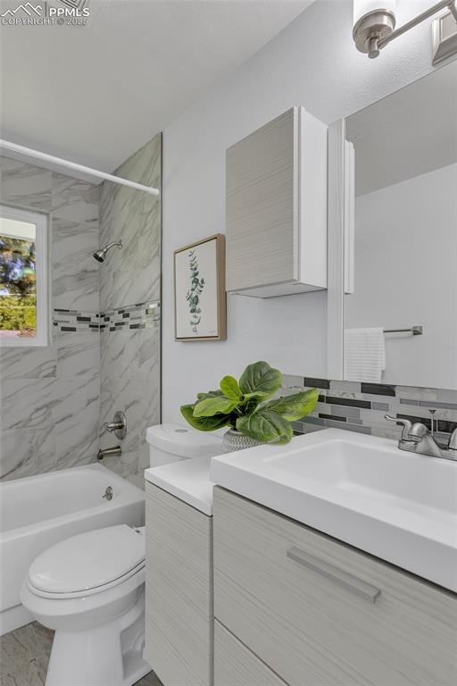 full bathroom with tiled shower / bath combo, vanity, and toilet