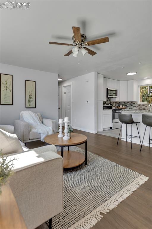 living room featuring ceiling fan and dark hardwood / wood-style floors