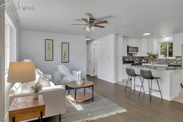 living room featuring ceiling fan and dark hardwood / wood-style floors