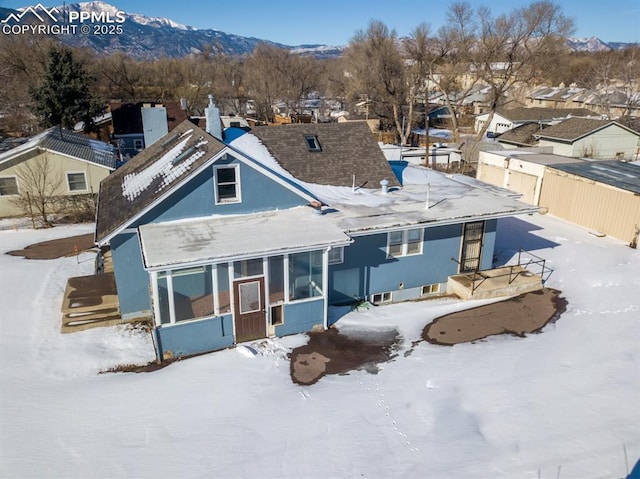 snow covered property featuring a mountain view and a sunroom