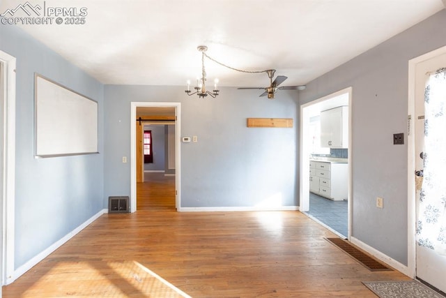 unfurnished dining area with ceiling fan with notable chandelier and light wood-type flooring