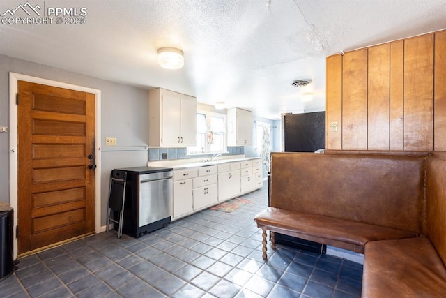 kitchen with refrigerator, sink, white cabinets, and a textured ceiling