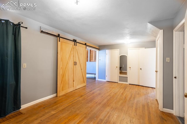 unfurnished room featuring a barn door and light hardwood / wood-style floors