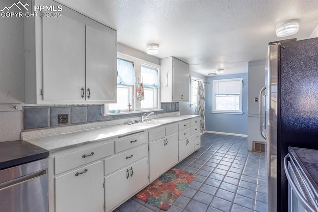 kitchen featuring white cabinetry, sink, range, and stainless steel refrigerator