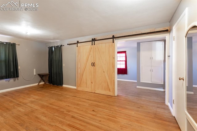 unfurnished bedroom with wood-type flooring and a barn door