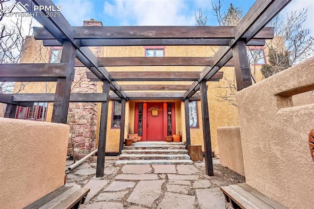 view of exterior entry featuring stone siding and a pergola