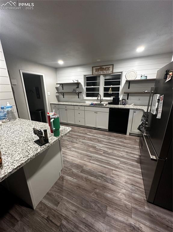 kitchen with sink, white cabinets, light stone counters, and black appliances