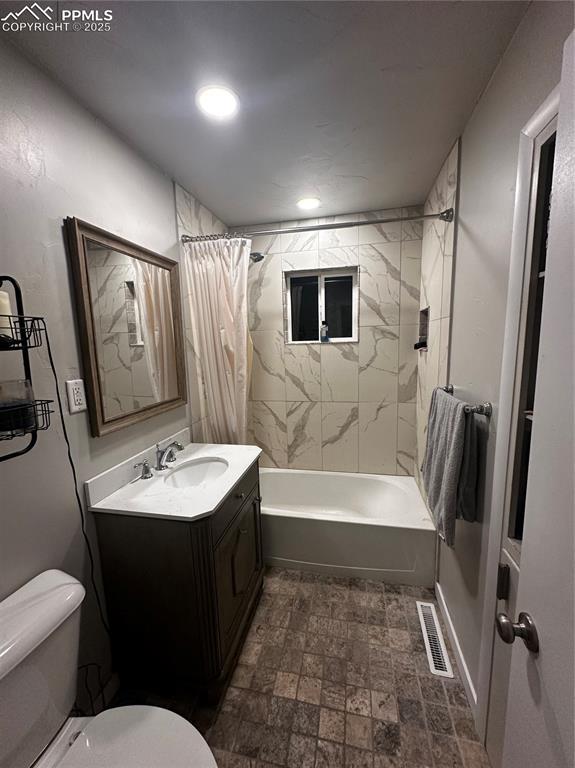 full bathroom featuring vanity, shower / bathtub combination with curtain, and toilet