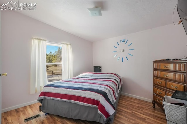 bedroom with wood-type flooring and vaulted ceiling