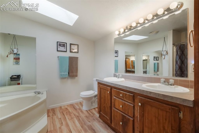 bathroom featuring hardwood / wood-style flooring, backsplash, lofted ceiling with skylight, vanity, and toilet