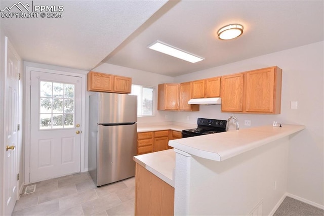 kitchen featuring black range with electric stovetop, light brown cabinets, stainless steel fridge, and kitchen peninsula