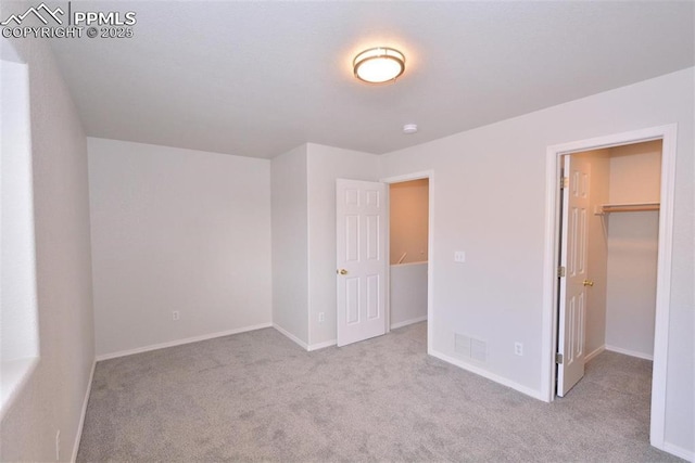 unfurnished bedroom featuring a spacious closet and light colored carpet