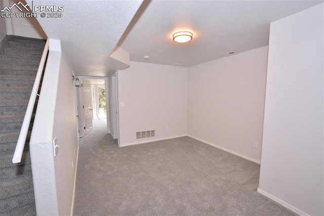 carpeted spare room featuring a textured ceiling