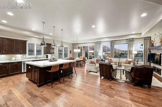 kitchen with sink, hanging light fixtures, a kitchen breakfast bar, a kitchen island, and stainless steel dishwasher